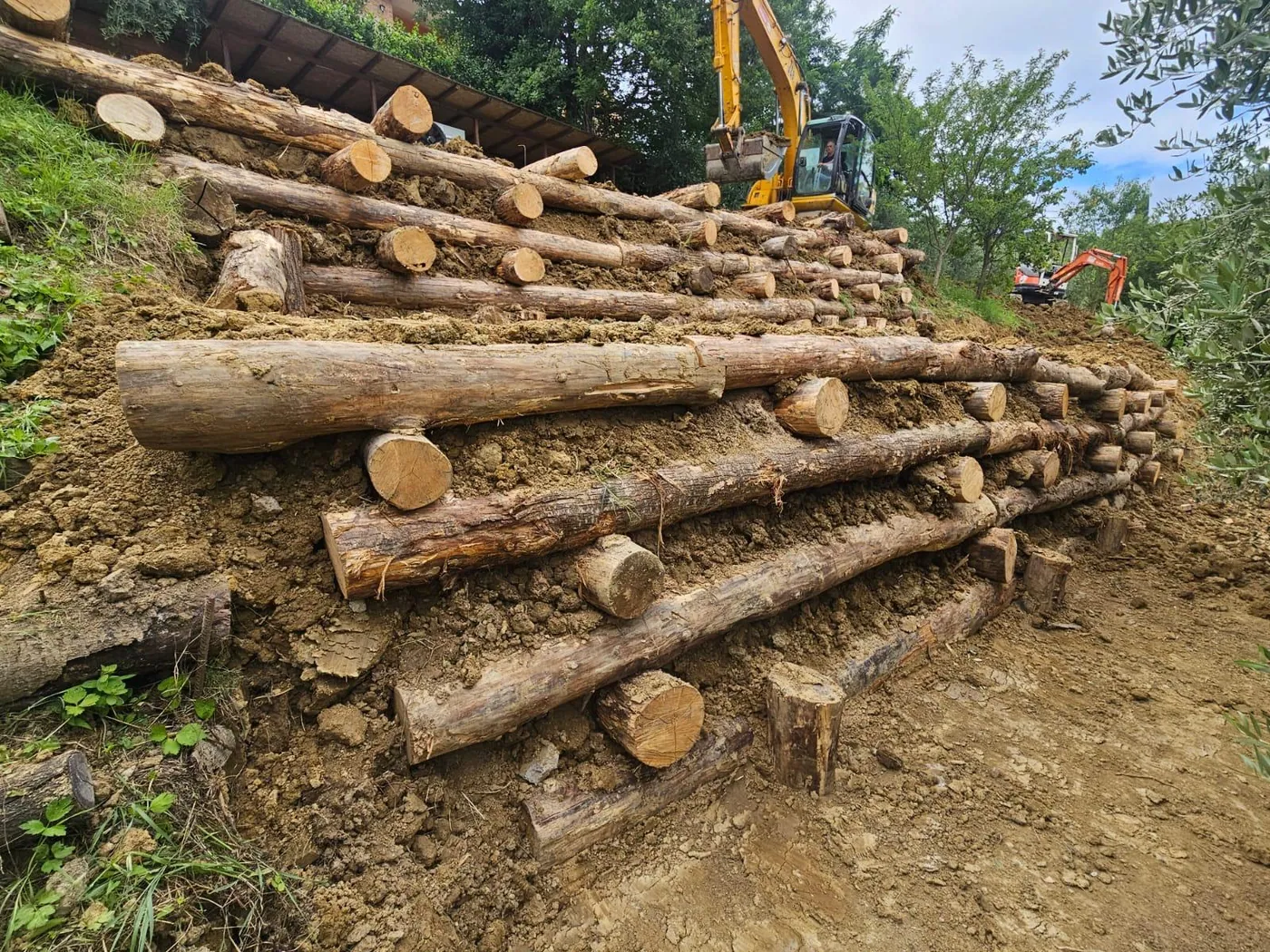 Realizzazione di palizzata in legno per il contenimento e la sistemazione del terreno, particolarmente adatta a scarpate, giardini, terrazzamenti e aree in pendenza.  L’intervento viene eseguito mediante la posa di elementi in legno opportunamente disposti e ancorati, con l’obiettivo di contenere il terreno, regolarizzare i dislivelli e creare una soluzione funzionale dal forte impatto naturale.  Ideale per: contenimento di scarpate, sistemazione di pendii, giardini, terrazzamenti e opere di inserimento paesaggistico.